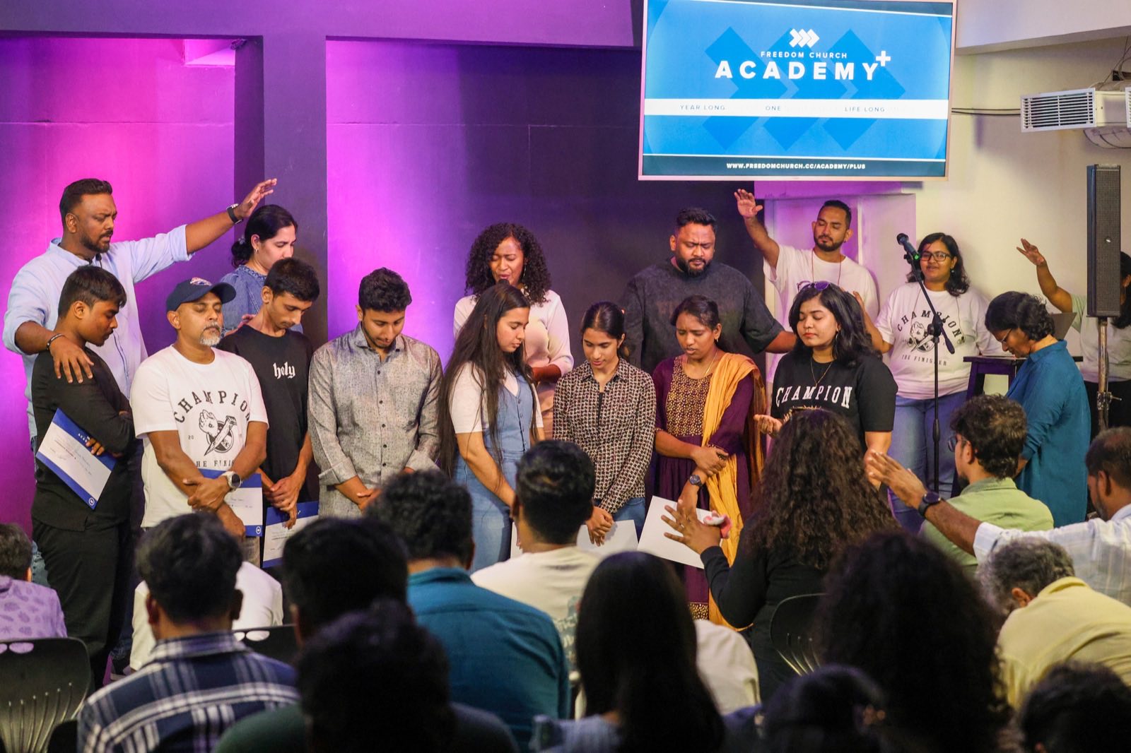Academy+ graduates being prayed over and commissioned on stage